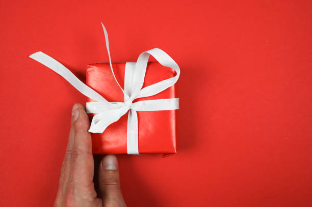 istock Red gift with a white ribbon in hand 1285496001