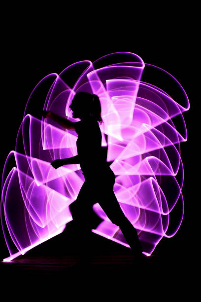 Lightpainting scene. Silhouette of a woman punching. Purple abstract form with saber light in the background. lightpainting stock pictures, royalty-free photos & images