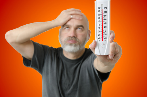 Man holding thermometer during heat wave
It shows more than 110F or 40C.
He has his head in his hand