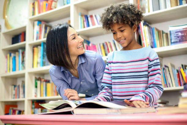 Learning Girl and her teacher in a school library. Two people, about 9-10 years old, mixed multi-ethnic group. librarian stock pictures, royalty-free photos & images