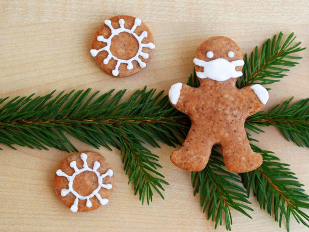 istock Gingerbread man with protective face mask on spruce twig and coronaviruses 1285508627