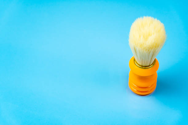Orange shaving brush on blue background, copy space. Skin care