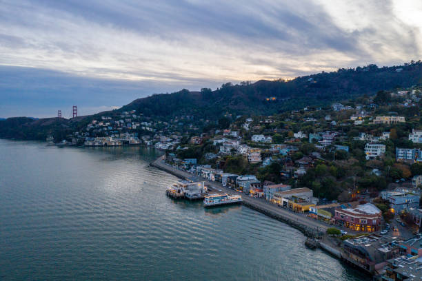 Aerial View of Sausalito at Sunset with Golden Gate Bridge Aerial view of Sausalito at dusk with the Golden gate Bridge looking over the hill. The artistic community is twinkling with lights as the sun sets. marin county stock pictures, royalty-free photos & images