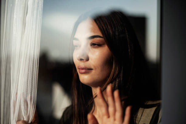 istock Woman wearing a mask looking out the window 1285509816