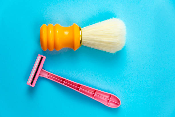 istock Pink razor and orange shaving brush on a blue background. 1285509817