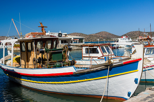 Colorful traditional Greek fishing boat moored at a small harbour in the town of Elounda, Crete