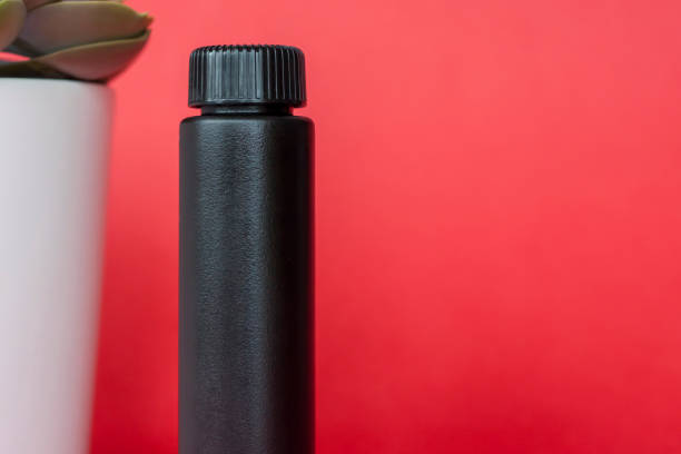 istock Black bottle with cream on a red background. 1285511671