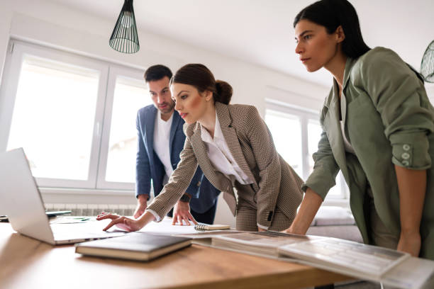 istock Young female architect showing renovation plans to her clients on a laptop 1285512941