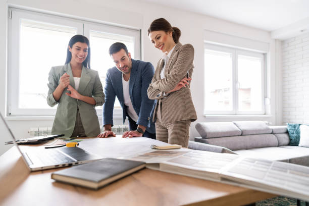 istock Young female architect showing renovation plans to a happy clients 1285512949