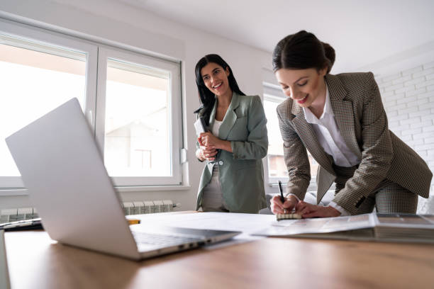 istock Two smiling young women making design plans and the female architect is writing down the notes 1285512963