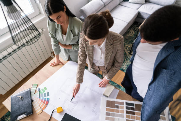 istock High angle view of a female architect talking about a home addition with a young couple while pointing to a blueprint 1285512964