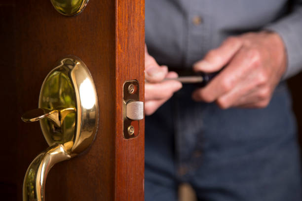 Worker or home owner installing or repairing new lock on doors. stock photo