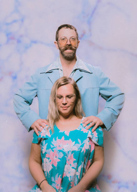 A late 1970's or early 1980's inspired photoshoot, a couple dressed in baby blue posing uncomfortably together.