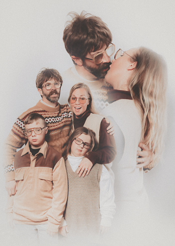 A Caucasian family poses for a portrait in the style of the late 1970's or early 1980's.  They wear matching brown and tan outfits.  The father and mother appear to be kissing or making out, a bit uncomfortable in the context.