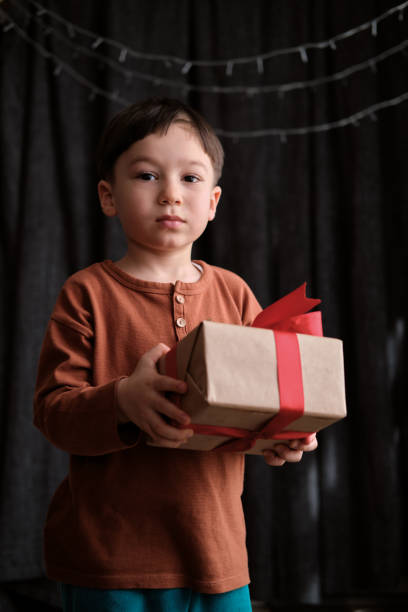 4-5-letnie dziecko trzyma pudełko na ciemnym tle na obchody bożego narodzenia - surprise child 4 5 years little boys zdjęcia i obrazy z banku zdjęć