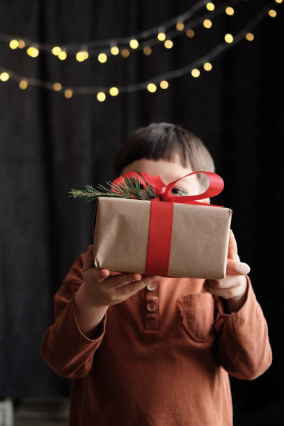 4-5-letnie dziecko trzyma pudełko na ciemnym tle na obchody bożego narodzenia - surprise child 4 5 years little boys zdjęcia i obrazy z banku zdjęć