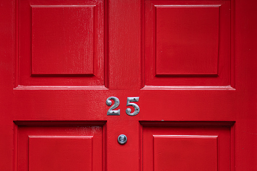 Detail of a red door with number 25 and peephole