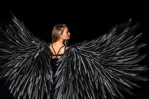 beautiful blonde girl dressed as a black angel on a black background