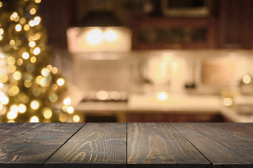 Wooden countertop and blurred kitchen with Christmas tree. Background for display or montage your products.