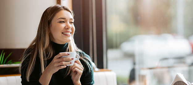 Beautiful cute girl in the cafe near the window with coffee smiling