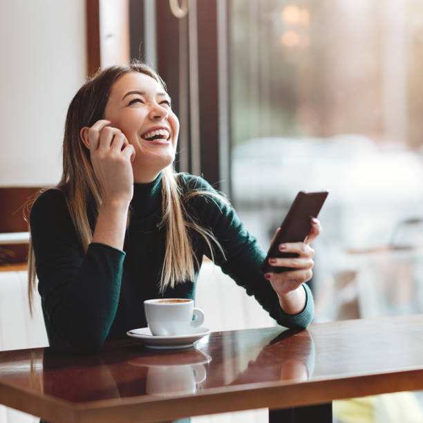 istock Young happy woman at restaurant drinking coffee and using mobile phone. 1285522377