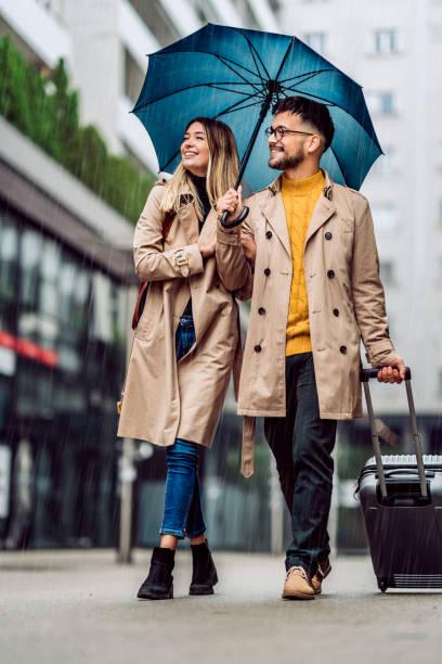 istock beautiful smiling young couple walking in the rain 1285523132