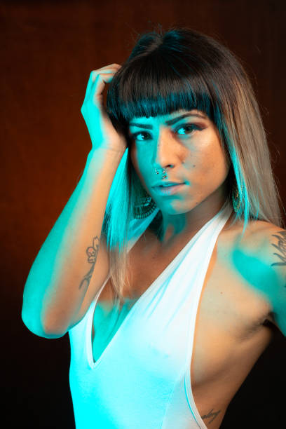 istock Young woman in leather bodysuit poses under teal side light 1285524569