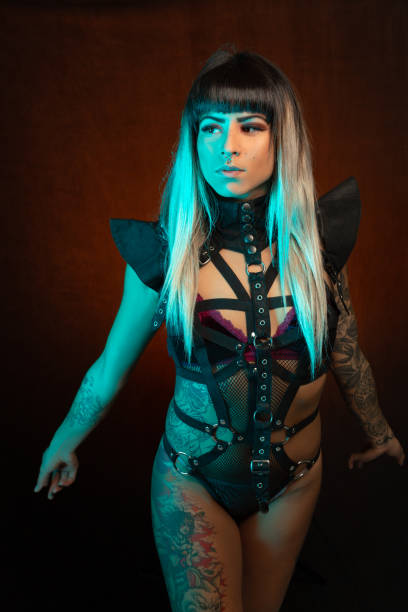 istock Young woman in leather bodysuit poses under teal side light 1285524580