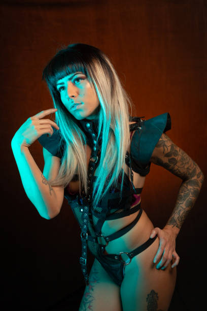 istock Young woman in leather bodysuit poses under teal side light 1285524635