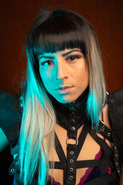 istock Young woman in leather bodysuit poses under teal side light 1285524636