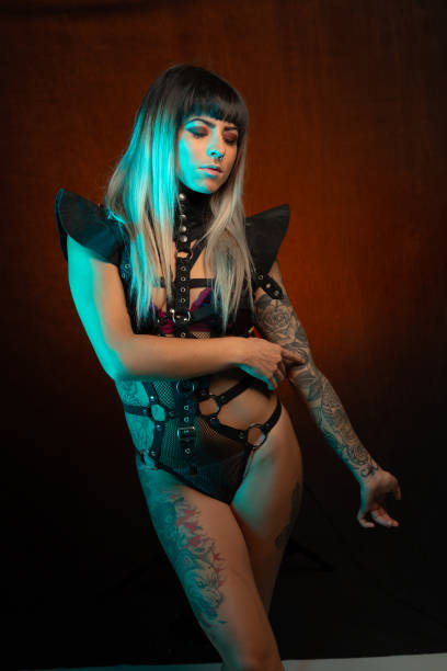 istock Young woman in leather bodysuit poses under teal side light 1285524659