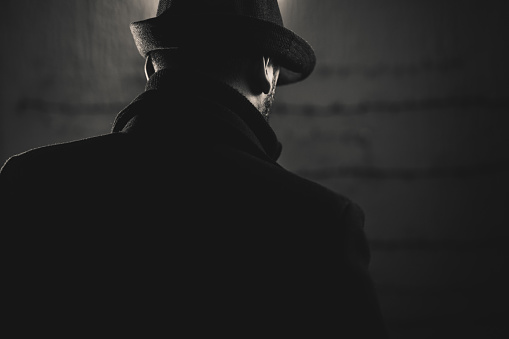 Retro man wears coat and hat, black and white. Noir style.