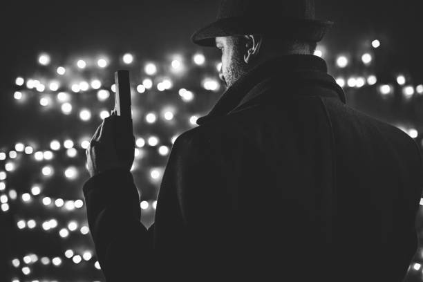 istock Retro man in coat and hat holding a gun 1285526688