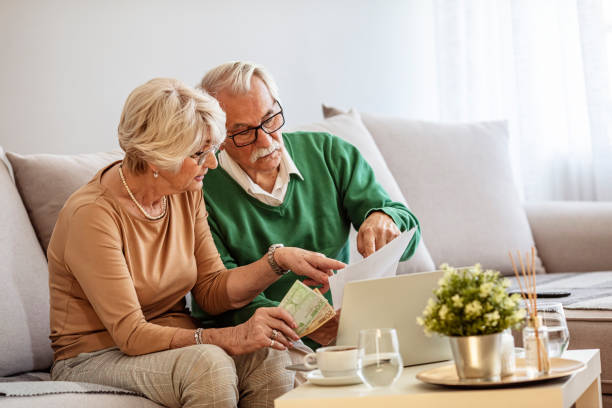 Worried Mature Couple Checking Finances And Going Through Bills Togethe