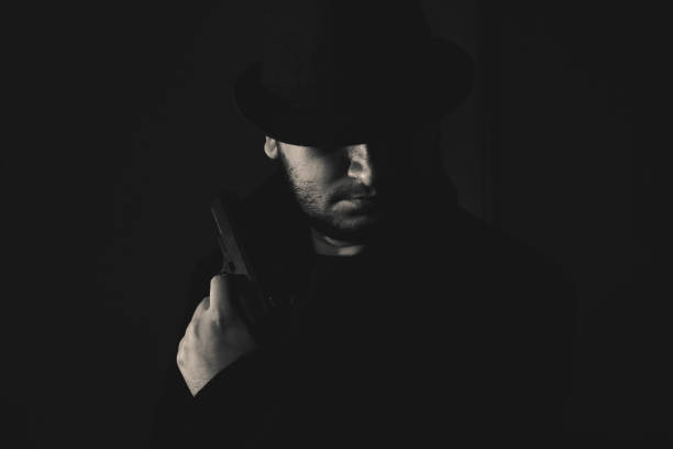 istock Retro man in coat and hat holding a gun 1285526713