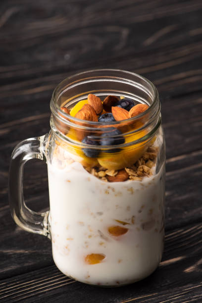 istock delicious granola with yogurt, nuts, peach, blueberry in glass jar 1285526837
