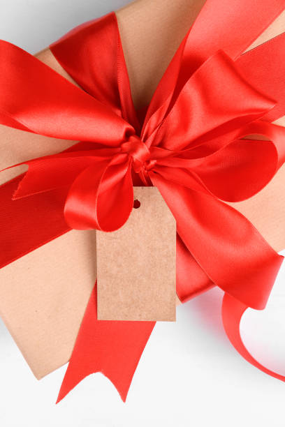 istock Empty craft gift tag mock up with gift box wrapped with red ribbon 1285530753