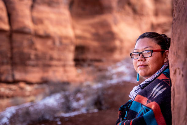 eine nahaufnahme eines indianers, navajo junge frau in einem traditionellen navajo wolle decke und sitzen in der ikonischen teardrop arch, monument valley, utah, arizona - monument valley navajo mesa monument valley tribal park stock-fotos und bilder