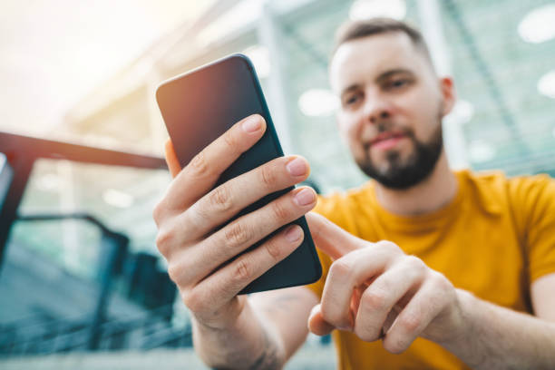 istock Young bearded man sitting at stadium steps and making bets online on his smartphone using mobile bookmaker application 1285530858