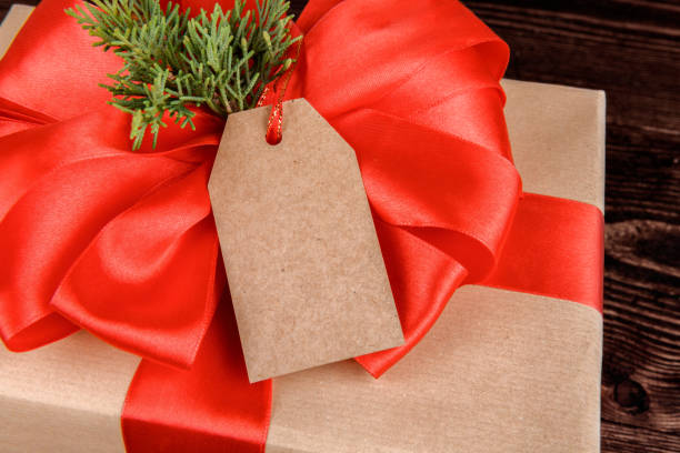 istock Empty craft gift tag mock up with gift box wrapped with red ribbon 1285531650