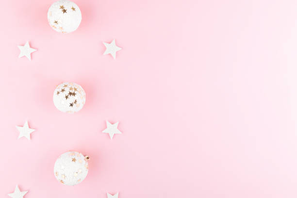 istock Christmas background with white balls, sequins on stylish pink table top view. Flat lay festive elegant composition 1285533973