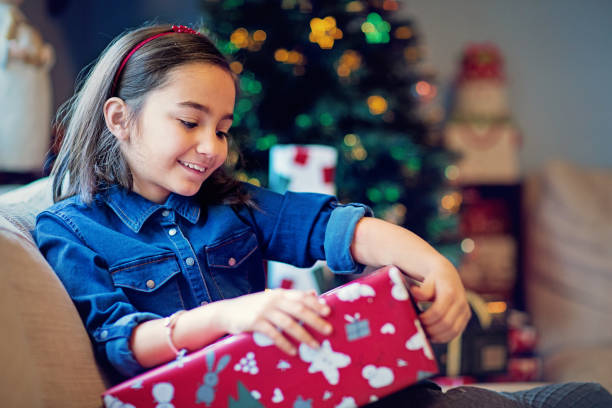 istock Happy girl is opening her Christmas present 1285534034
