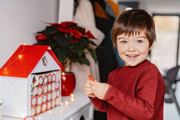 Little happy child opening first day in handmade advent calendar made from toilet paper rolls. Sustainable Christmas, upcycling, zero waste, kids seasonal activities stock photo