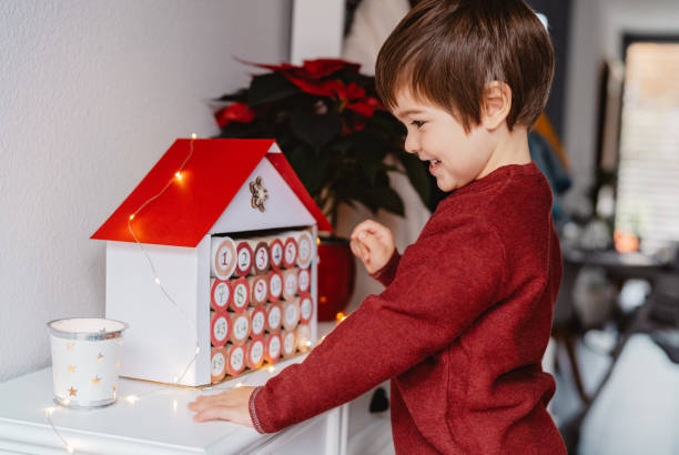 Little happy child opening handmade advent calendar made from toilet paper rolls. Sustainable Christmas, upcycling, zero waste, kids seasonal activities stock photo