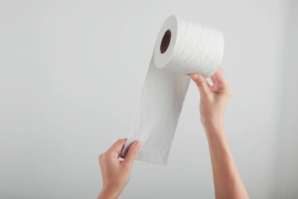 istock Hand holding white toilet paper roll over grey background 1285539202