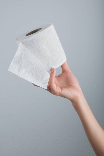 istock Hand holding white toilet paper roll over grey background 1285539243