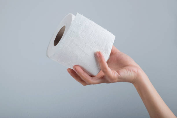istock Hand holding white toilet paper roll over grey background 1285539265