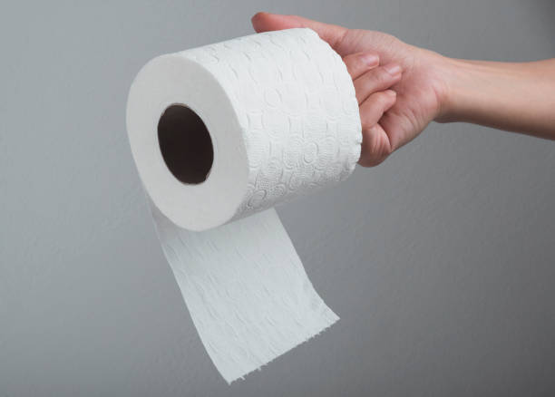 istock Hand holding white toilet paper roll over grey background 1285539289