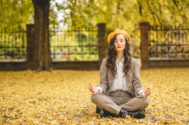 kobieta praktykująca jogę i ciesząc się w jesienny dzień - zen like nature breathing exercise sitting zdjęcia i obrazy z banku zdjęć