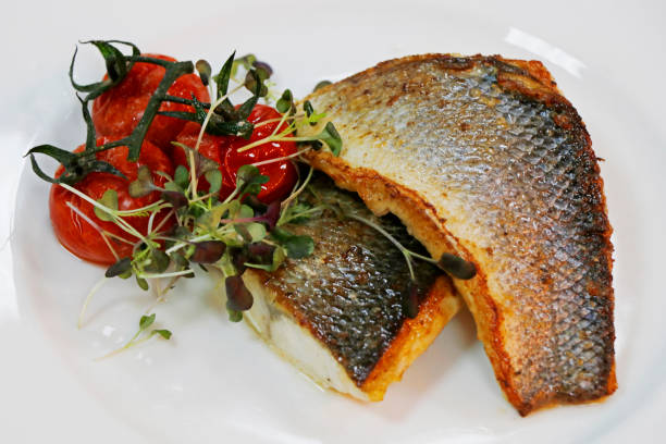 istock pan fried grill seabass fish fillet with tomato and herbs on a white plate 1285543537